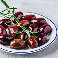 Black olives with olive oil and rosemary branch on a plate